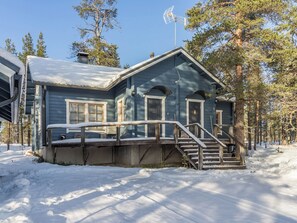 Een chalet met twee verdiepingen, een overdekte veranda en een trap naar de ingang.