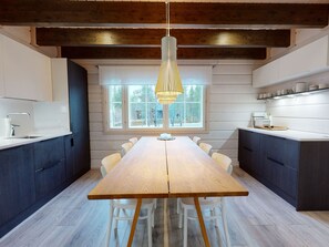 A modern kitchen with a central island, wooden flooring, and a large window providing a view of the outdoors.