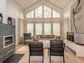 A spacious living room with a stone fireplace, a large window, a sofa, and a television.