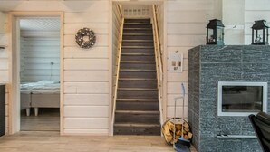 Eine Treppe führt zu einem Schlafzimmer, ein Kamin mit Laternen und ein Kranz an der Wand.