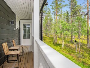 Ett trädäck med två stolar och en dörr som leder ut till en inglasad veranda.