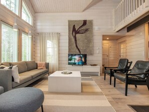 A modern living room with a sofa, coffee table, TV, and chairs.
