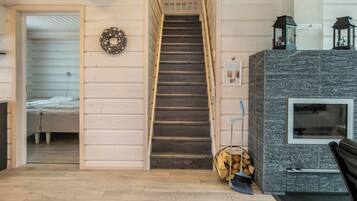 A staircase leading to a bedroom, a fireplace with a stone surround, and a wall-mounted lantern.