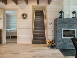 A staircase leading to a bedroom, a fireplace with a stone surround, and a wall-mounted lantern.