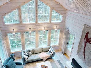 A spacious room with a large windowed wall, a sofa, a television, and a fireplace. - Sokosti by Interhome (Inari)