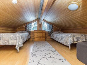 A wooden cabin bedroom with two beds, a dresser, and a window. - Aihki 1 by Interhome (Inari)