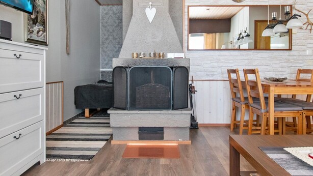 Ein modernes Wohnzimmer mit Kamin aus Stein, einem Essbereich mit Holzsesseln und einer Wand aus weißen Ziegeln.