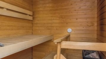 En sauna med trævægge, en bænk og en lille skraldespand.