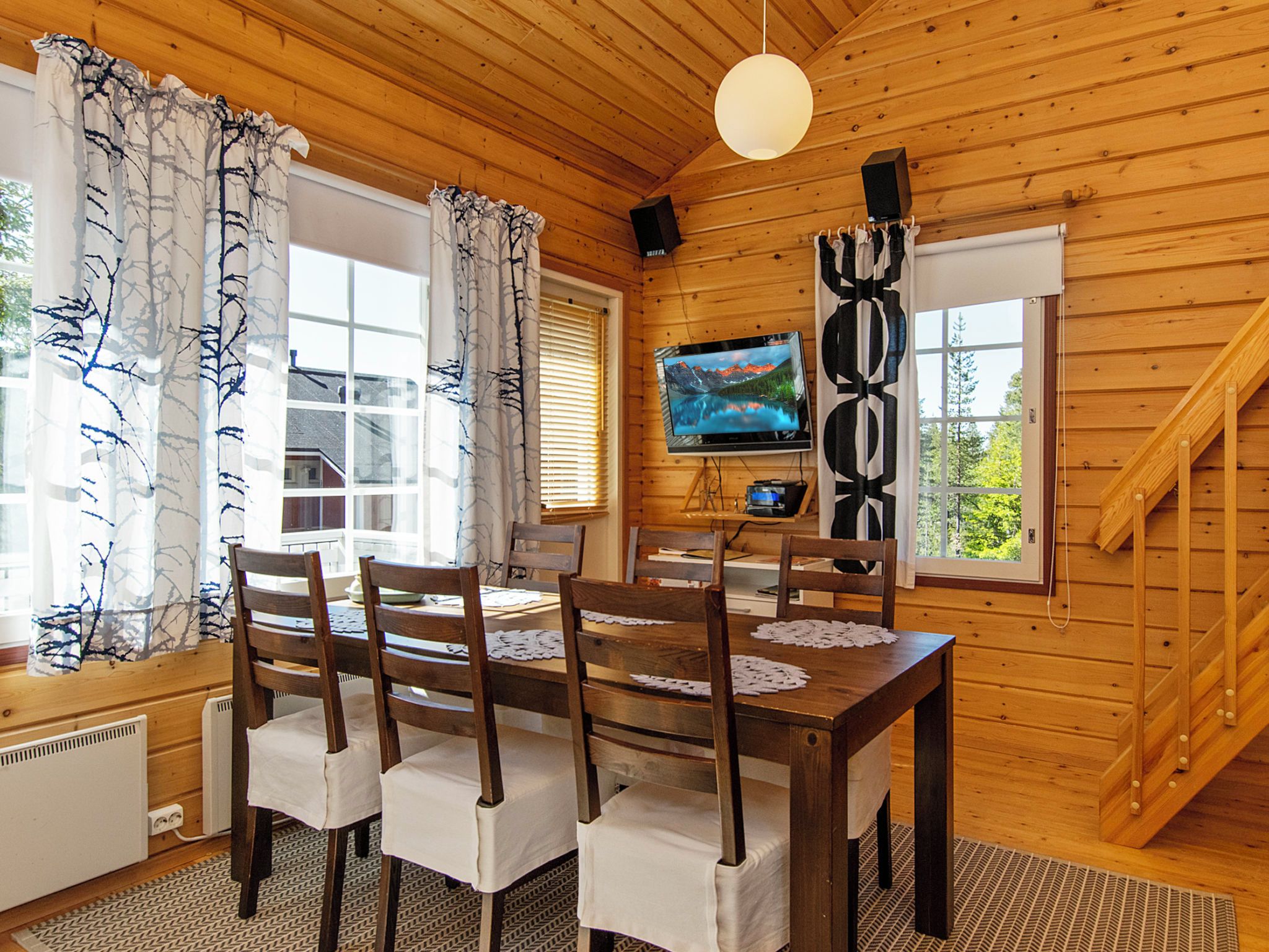 Un intérieur en bois comprenant une table à manger, des chaises, un téléviseur et un escalier.