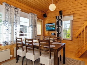 Un intérieur en bois comprenant une table à manger, des chaises, un téléviseur et un escalier.