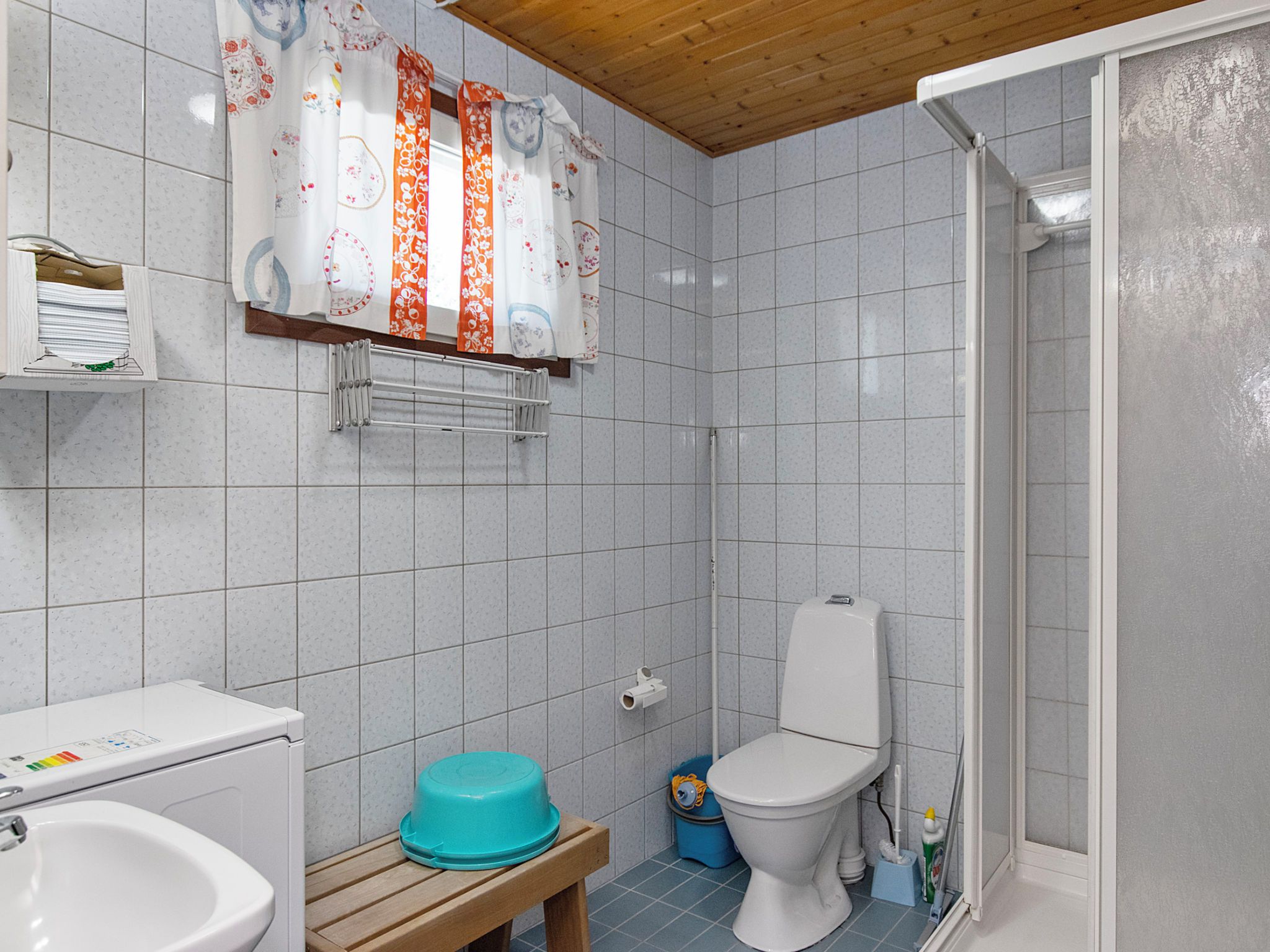 A bathroom with a toilet, sink, shower, and a wooden bench.