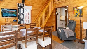 Interior acogedor de una cabaña de madera con comedor, sala de estar y una escalera.