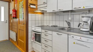 Una cocina moderna con gabinetes blancos, estufa, lavavajillas y cafetera.