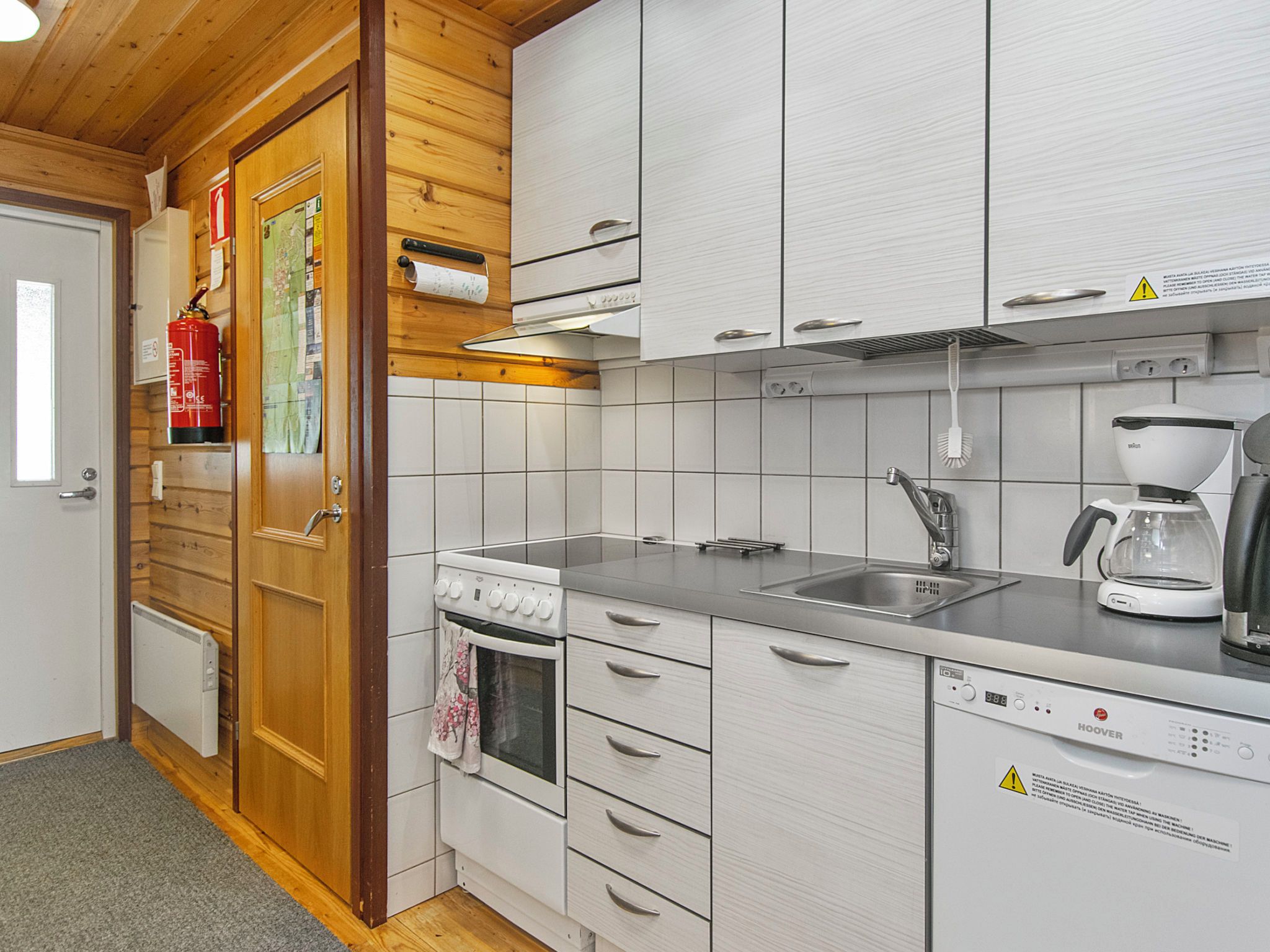A modern kitchen with white cabinetry, a built-in oven, a coffee maker, and a dishwasher.