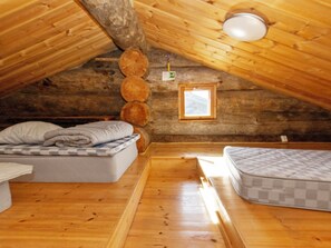 A cozy attic bedroom with wooden walls, a loft bed, a small window, and a ceiling light fixture. - Kauniskelo a by Interhome (Inari)