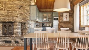 Una cocina rústica con paredes de piedra, techo de madera y una lámpara colgante grande.