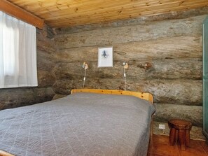 A log cabin bedroom with a bed, a small stool, and a framed picture on the wall. - Kauniskelo a by Interhome (Inari)