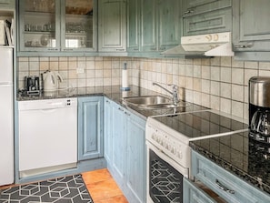 Une cuisine équipée d’un lave-vaisselle, d’une cuisinière, d’un évier et de placards.