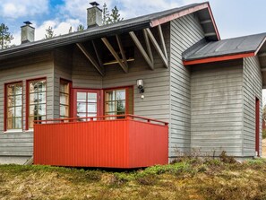 Une maison avec un balcon rouge, un revêtement extérieur gris et une cheminée.
