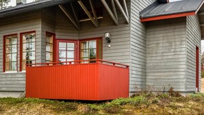 Una casa con un porche rojo, revestimiento gris y una chimenea.