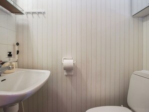 A bathroom with a white sink, toilet, and a paper towel dispenser mounted on the wall.