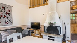 Una sala de estar con chimenea, televisor, sofá y mesa de comedor.