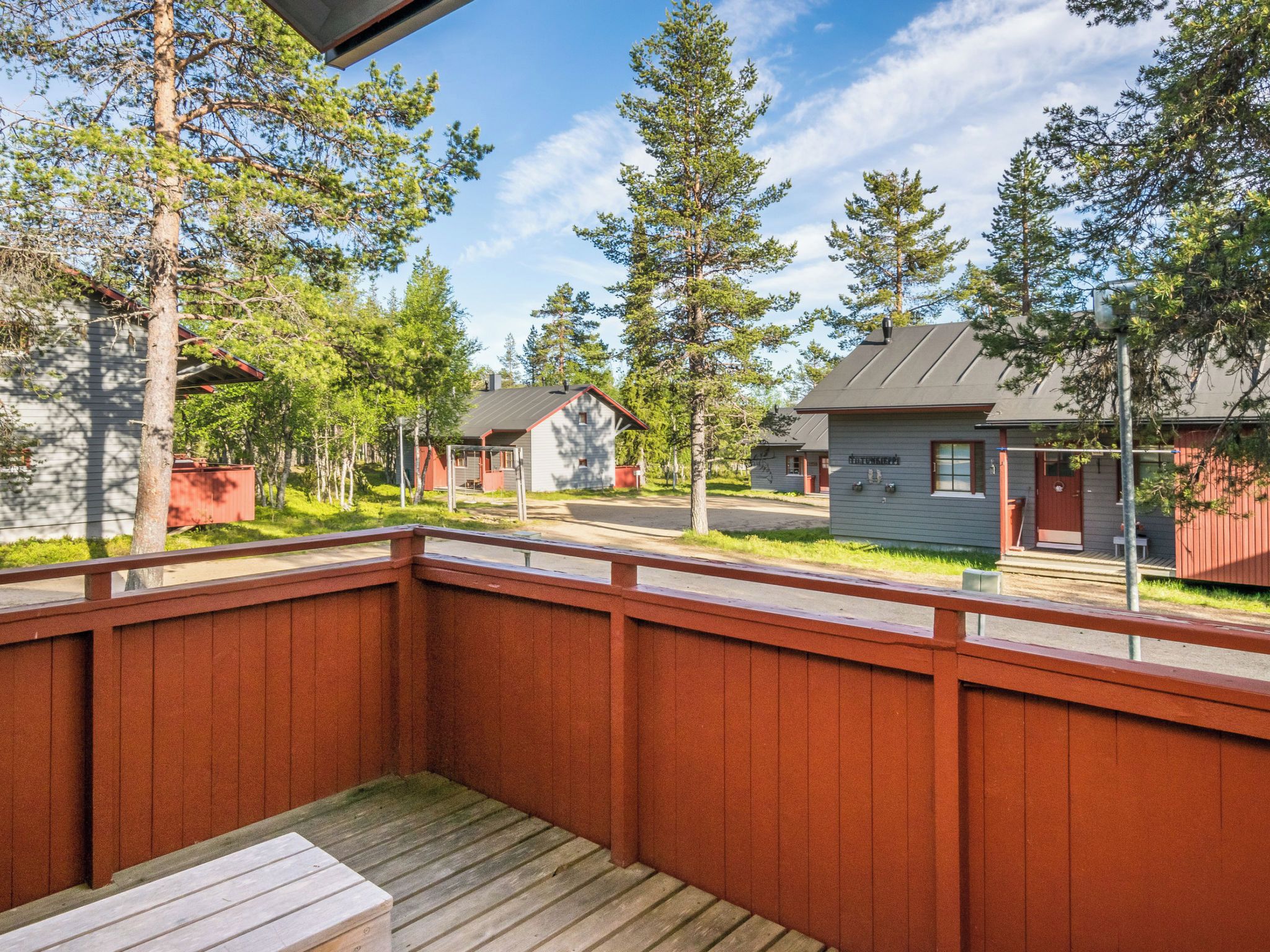 Une terrasse en bois offrant une vue sur les chalets et les arbres.