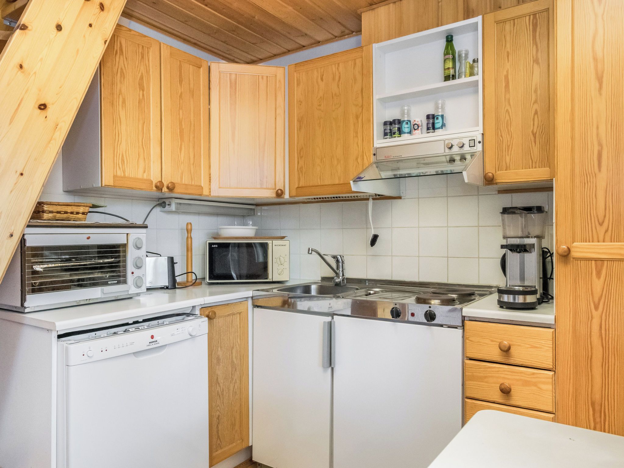 Een keuken met houten kastjes, een magnetron, een fornuis en een vaatwasser.