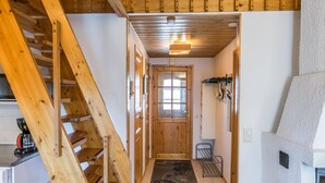 Una escalera de madera que conduce a una habitación con una puerta, una silla pequeña y un radiador.