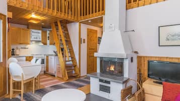 A cozy interior with a fireplace, wooden staircase, and a dining area.
