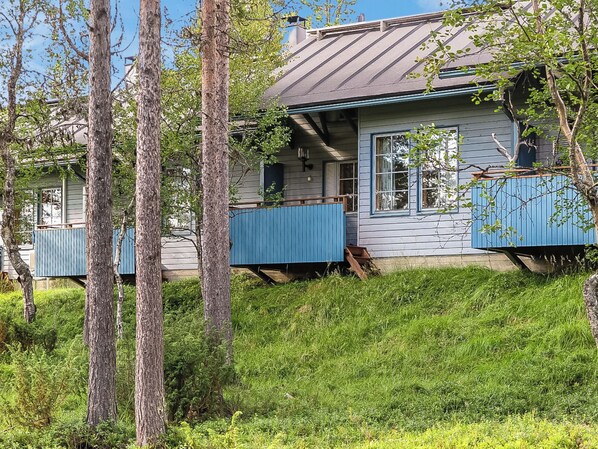 Une maison avec un toit en pente, un revêtement en bois et un porche bleu à l’avant.