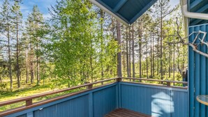 Terraza de madera con baranda azul que da vista a un área boscosa.
