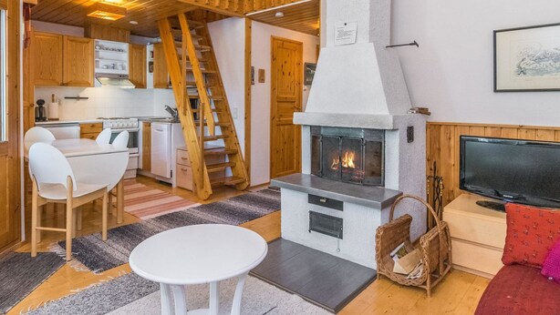 Acogedor interior de cabaña con comedor, cocina, chimenea y televisor.