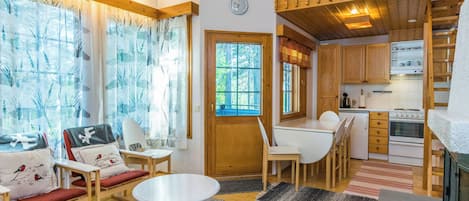 Un intérieur de chalet chaleureux comprenant un coin repas, une cuisine et une chambre à coucher située en mezzanine.