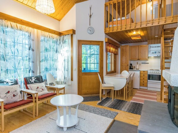 Un intérieur de chalet chaleureux comprenant un coin repas, une cuisine et une chambre à coucher située en mezzanine.