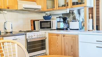 Ett kompakt kök med träskåp, en mikrovågsugn, en kaffebryggare och en ugn från Siemens.