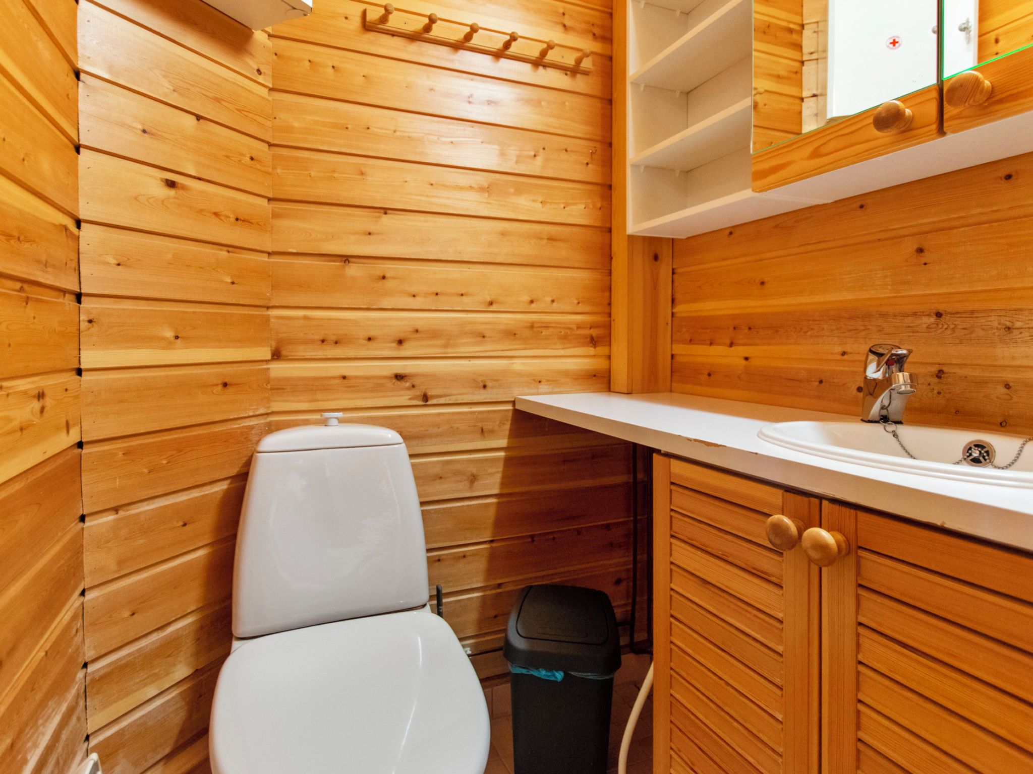 Une petite salle de bain en bois comprenant des toilettes, un lavabo et un meuble de rangement.