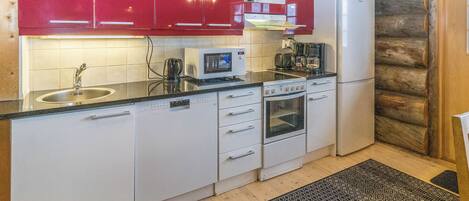 Una cocina con armarios superiores rojos, un refrigerador blanco, un microondas Siemens, una cafetera y una estufa.