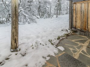 A snow-covered pathway leading to a wooden building with a stone-tiled entrance.