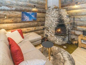 A log cabin interior with a stone fireplace, a sofa with cushions, and a painting on the wall.