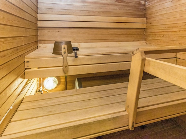 A sauna with wooden benches and a metal basin.