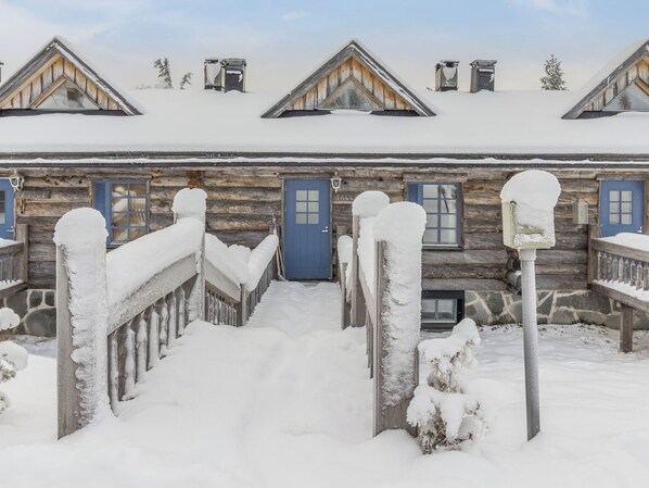 A snow-covered wooden building with a central entrance and multiple windows.