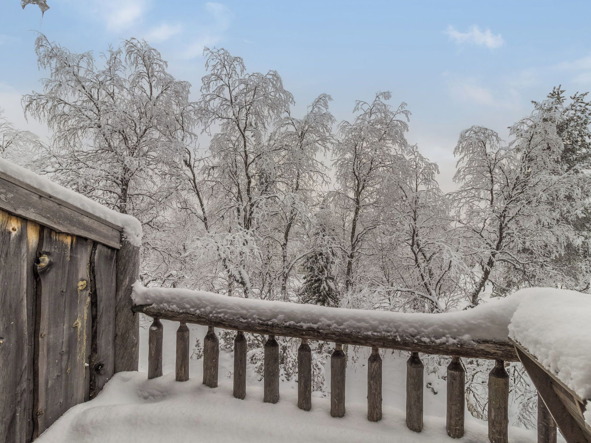 A wooden balcony railing with snow accumulation.
