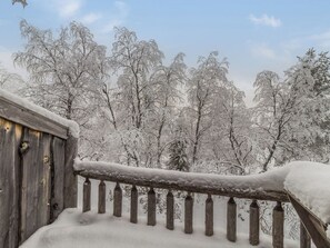 A wooden balcony railing with snow accumulation.
