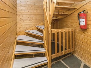 A wooden staircase with a fire extinguisher mounted on the wall.