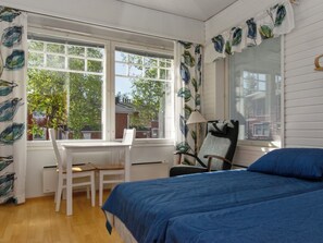 Una habitación con cama, escritorio y silla. Hay ventanas con cortinas.