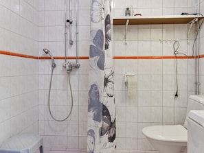 A bathroom with a shower, toilet, and a towel rack.