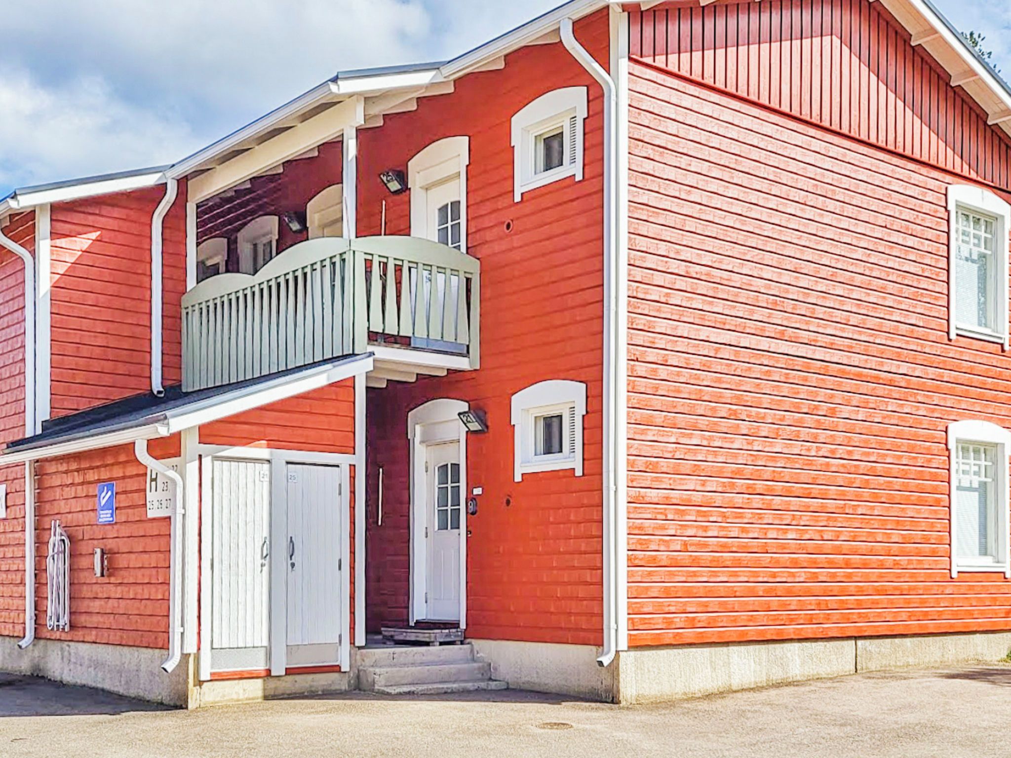 Un edificio rojo con un balcón, una puerta blanca y una ventana pequeña.