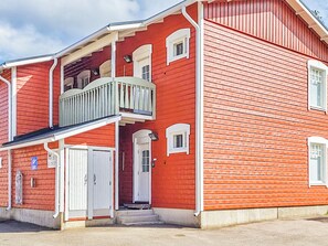 A red building with a balcony, a white door, and a small window.