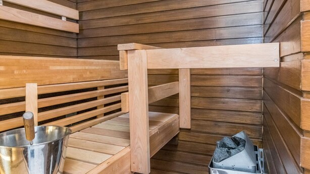 Una sauna de madera con bancos y un balde de metal.